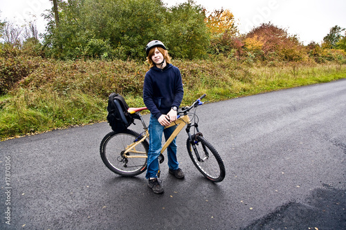 Jugendlicher mit Fahrrad bei regen auf Fahrradtour