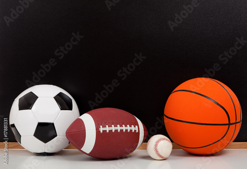 Assorted sports balls with a black chalk board background