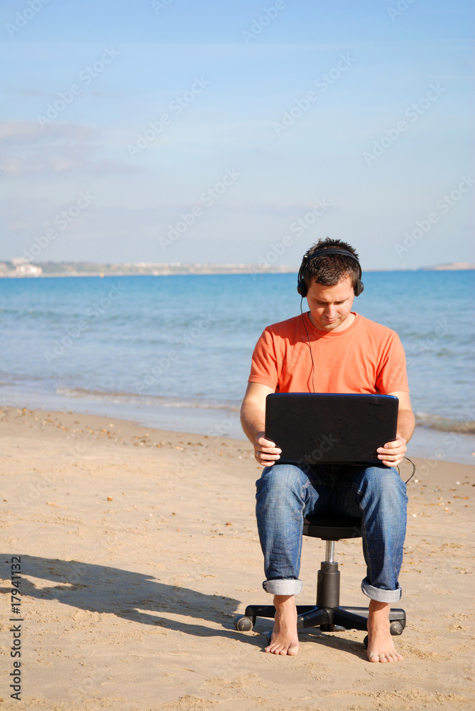 Man with headphones & laptop at the beach