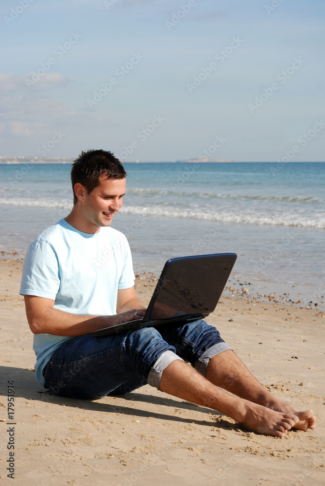 Man sat on the beach with laptop