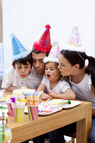Little girl blowing out candles in her birthday's day with famil