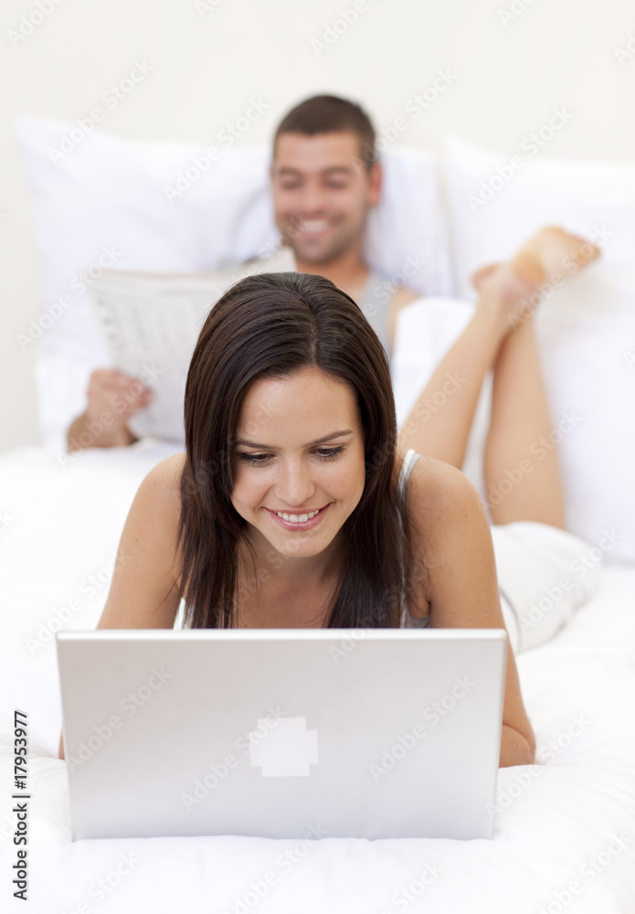Woman using a laptop and man reading a newspaper Woman using a laptop and man reading a newspaper