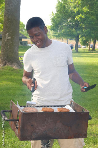 Teen Boy Grilling Hamburgers at a Park
