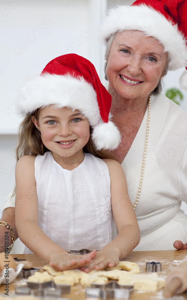 Fotografie Smiling grandmother and little girl baking Christmas cakes