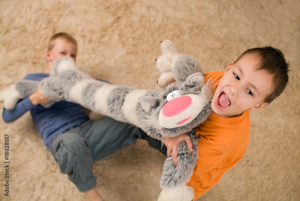 Naklejka premium Two kids with a toy cat on the floor
