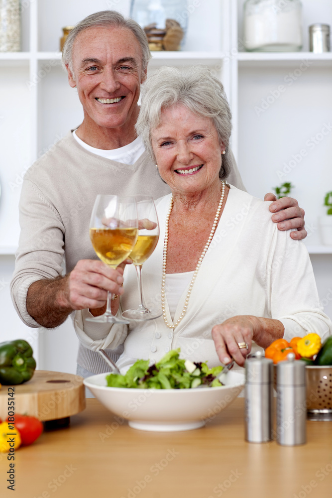 Happy senior couple eating a salad in the kitchen