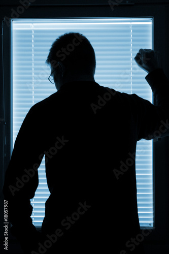 Silhouette of a man standing by the window