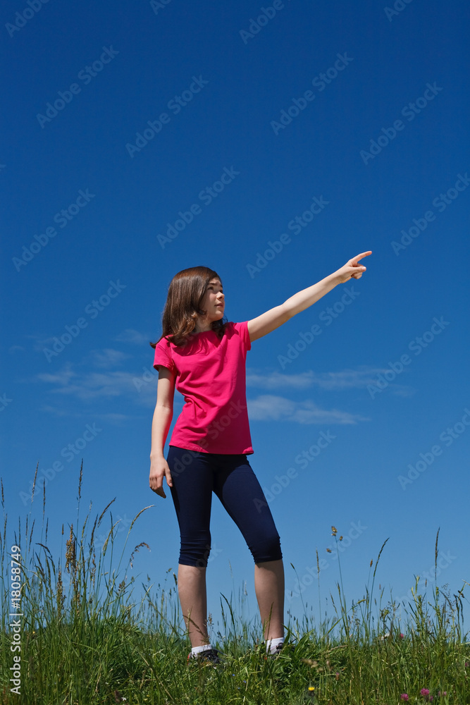 Girl pointing standing against blue sky Girl pointing standing against blue sky