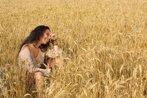 Attractive girl sitting in golden wheat