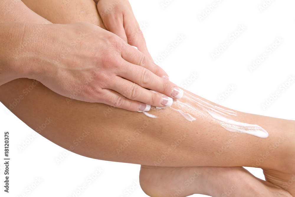 Fototapeta premium Putting lotion on leg with hand