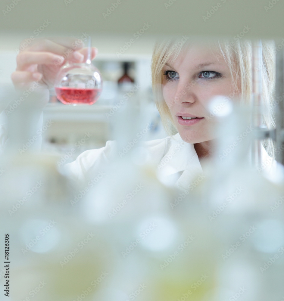 Closeup of a female researcher holding up a test tube and a reto Closeup of a female researcher holding up a test tube and a reto