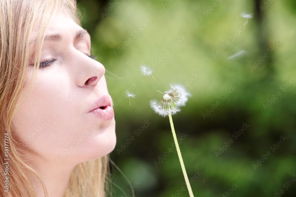 The blonde in park with a dandelion in hands The blonde in park with a dandelion in hands