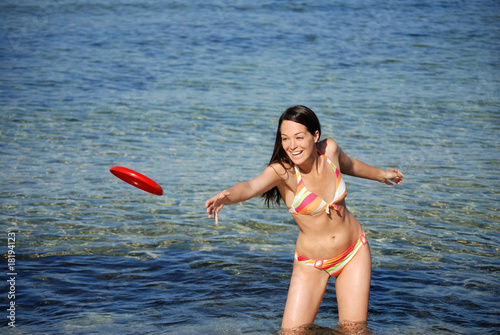 Woman throwing frisby at the beach photo