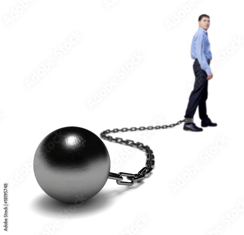 Man's legs dragging a ball and chain, selective focus.