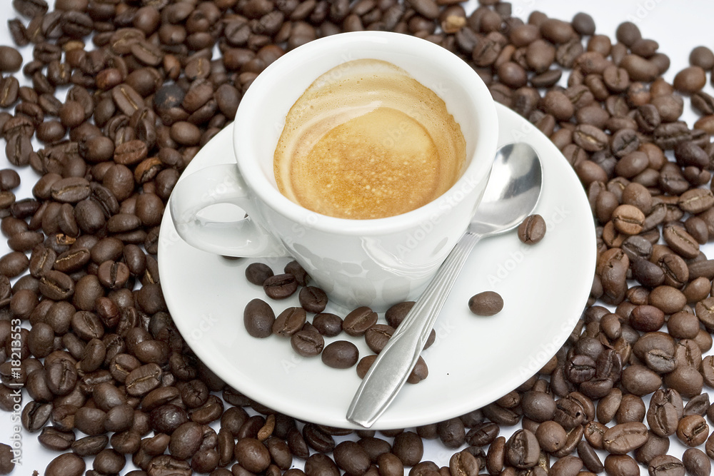 Fototapeta premium Cup of coffee sitting in a bed of coffee beans