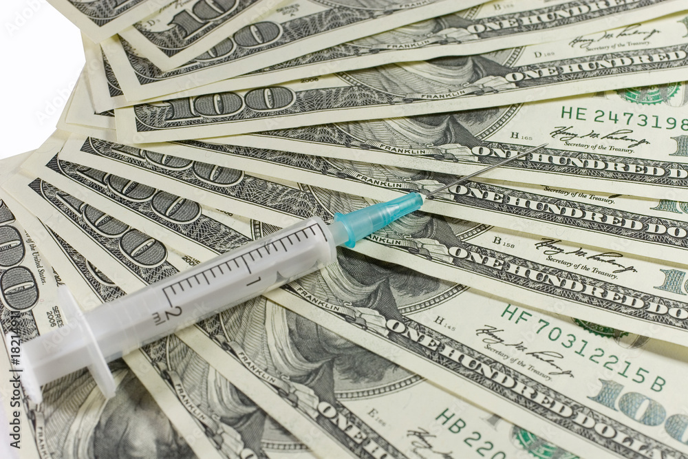 Closeup of a syringe on US dollars (isolated on white) Closeup of a syringe on US dollars (isolated on white)