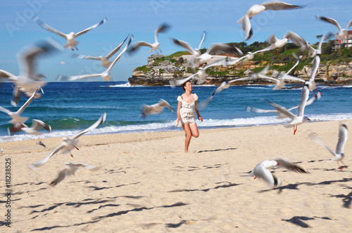 Beautiful young girl runs on Bondi Beach, chasing seagulls
