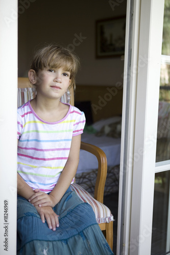 little cute girl sitting on chair on verandah