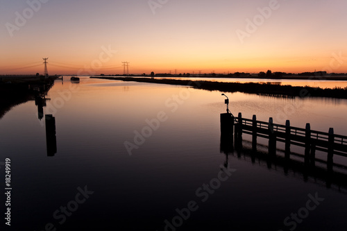 Beautiful sunrise above a dutch river while a ship is approachin