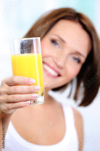 Happy female holds a glass of orange juice