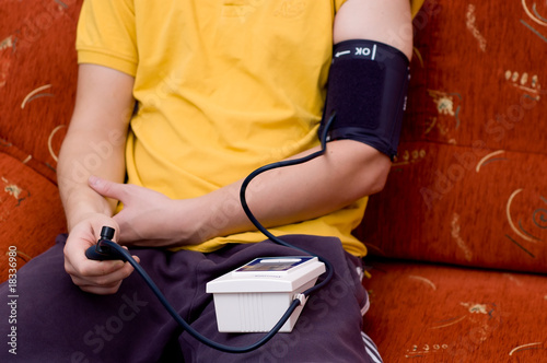 Man in yellow shirt is checking his blood pressure
