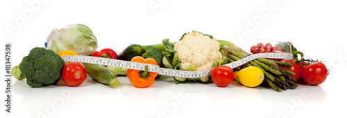 A row of vegetables and a tape measure on white