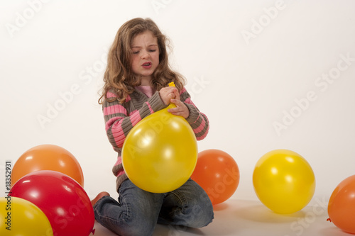 little girl struggling to tie balloon