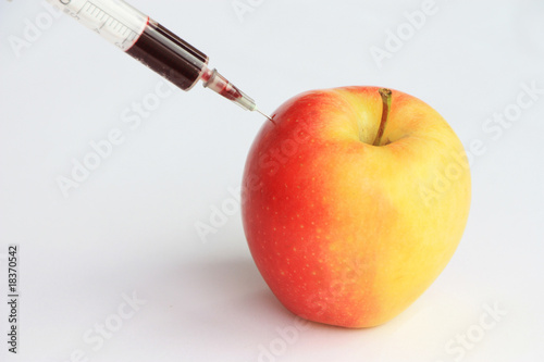 seringe injecting red liquid into an apple photo