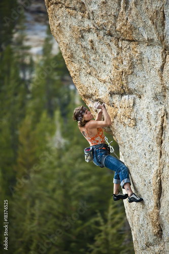 Female climber clinging to a cliff.