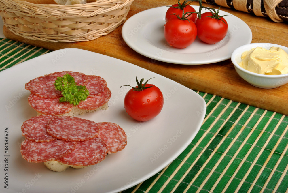 half bread roll with salami on a plate