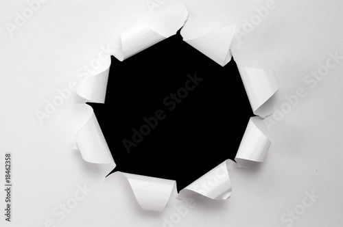 Hole torn in paper on black background