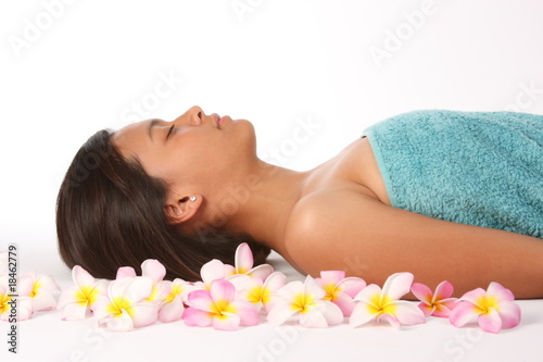 Young woman completely relaxed in health spa amongst frangipanis