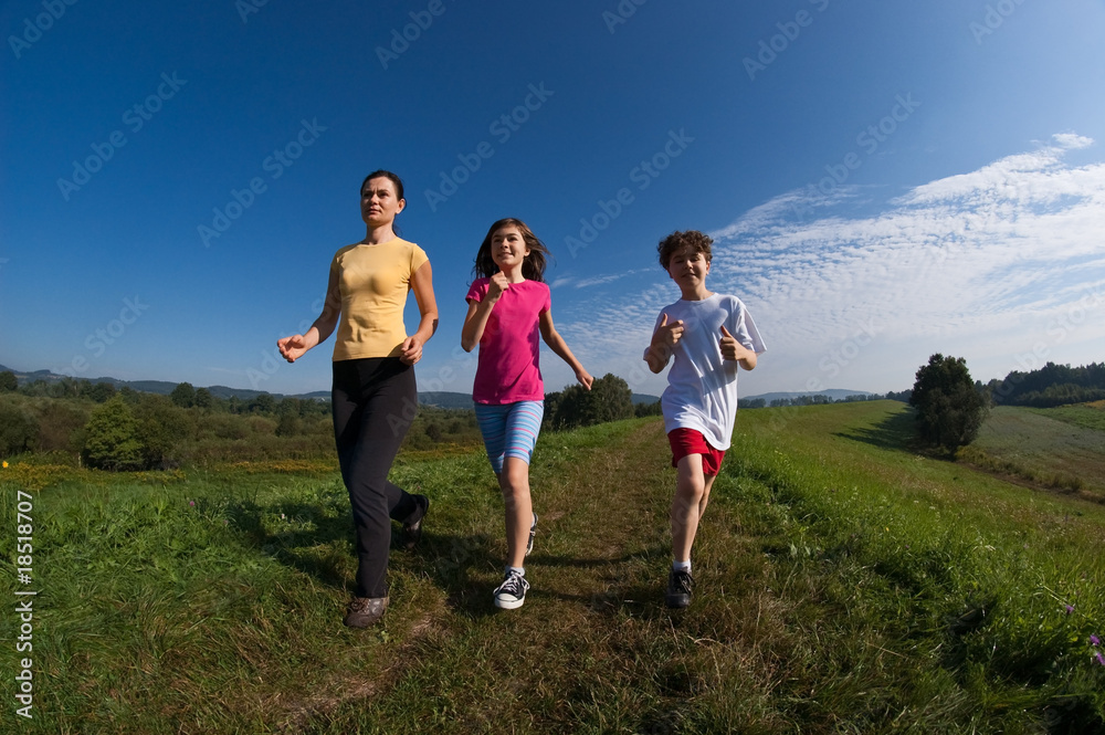 Active family - mother and kids running on green meadow Active family - mother and kids running on green meadow
