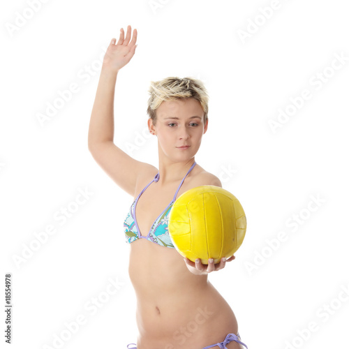 Teen woman in bikini playing volleyball