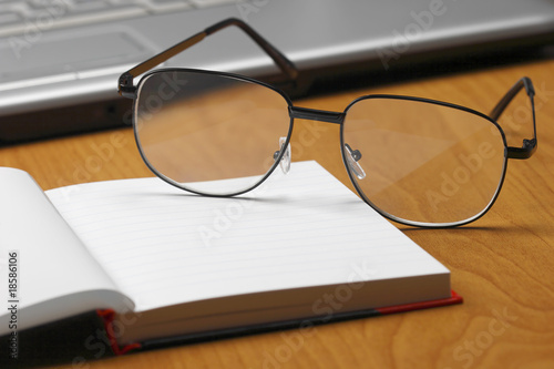 Eyeglasses,laptop and notebook.