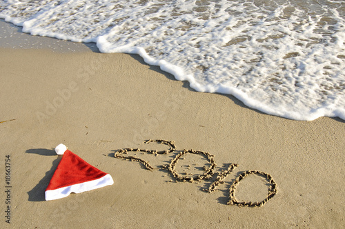 Santa hat with New Year on the sand with wave.