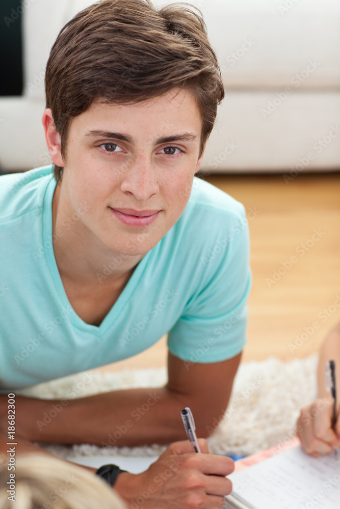 Teen guy studying on the floor with his friends Teen guy studying on the floor with his friends