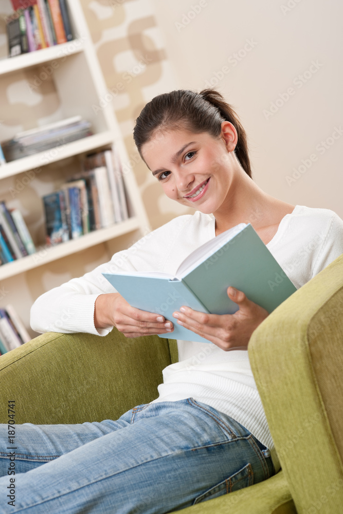Students - Happy teenager with book sitting on armchair Students - Happy teenager with book sitting on armchair