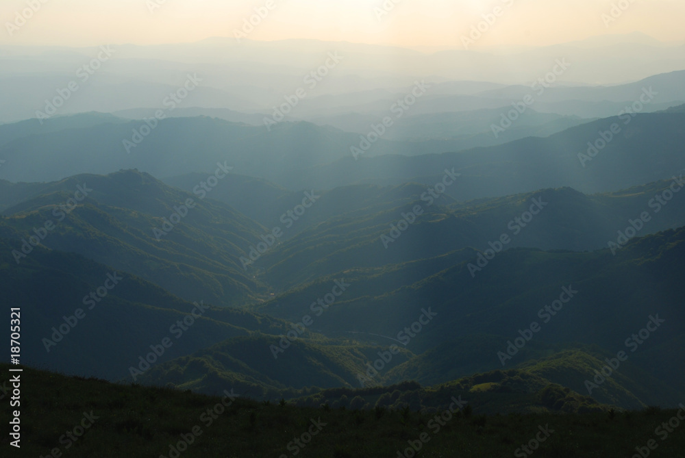 Fototapeta premium sunbeams passing trough clouds over hills