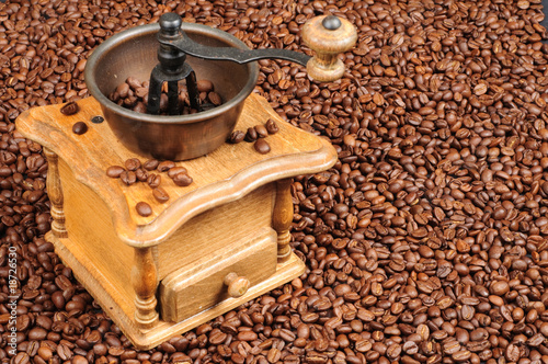 Old fashioned coffee grinder on a background of coffee beans
