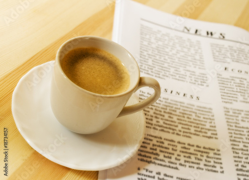 A cup of hot coffee, and newspaper.