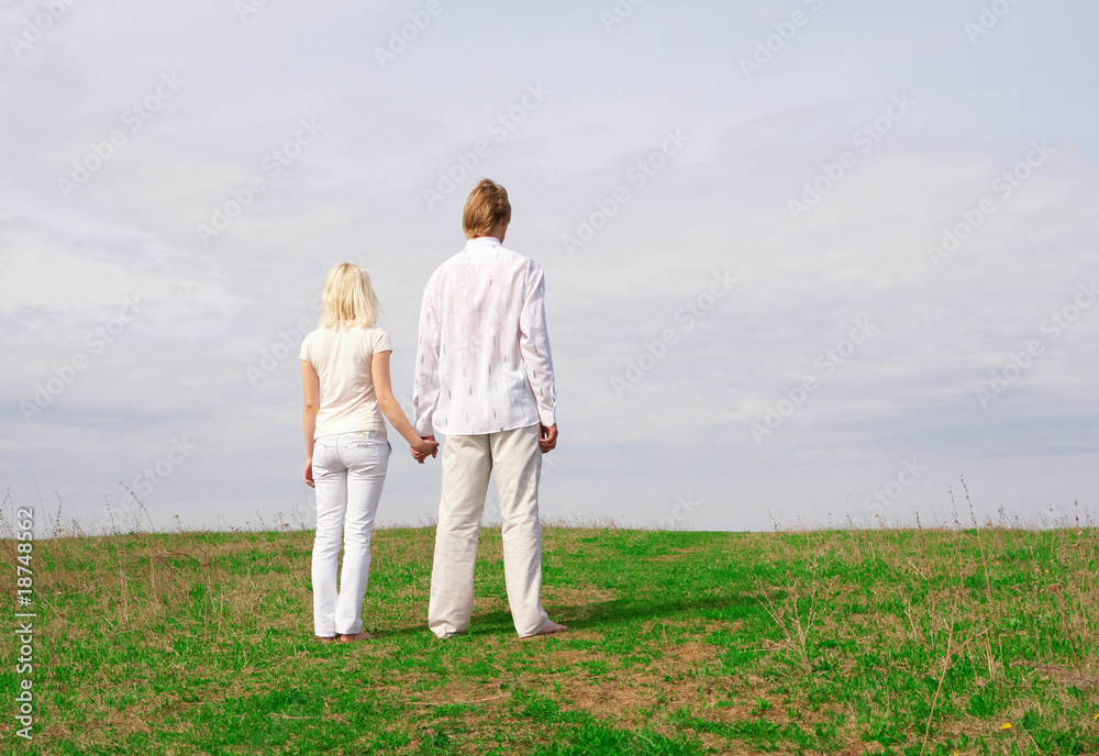 Guy and girl standing on the green meadow