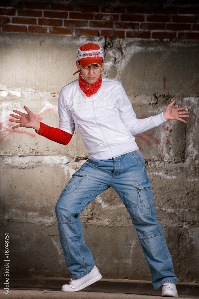 Hip hop boy dancing in modern style over grey brick wall