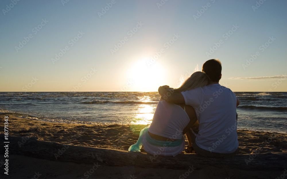 Couple sitting near the sea on sunset Couple sitting near the sea on sunset