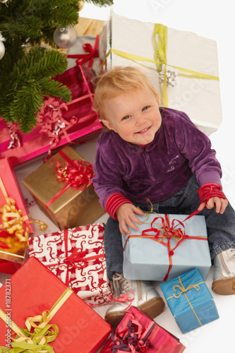 Cute baby looking up with christmas gifts