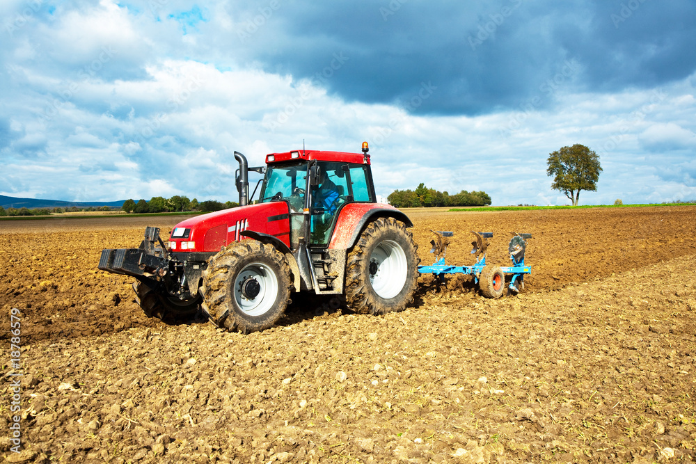Traktor pflügt ein Feld um, Himmel ist blau schwarz Traktor pflügt ein Feld um, Himmel ist blau schwarz