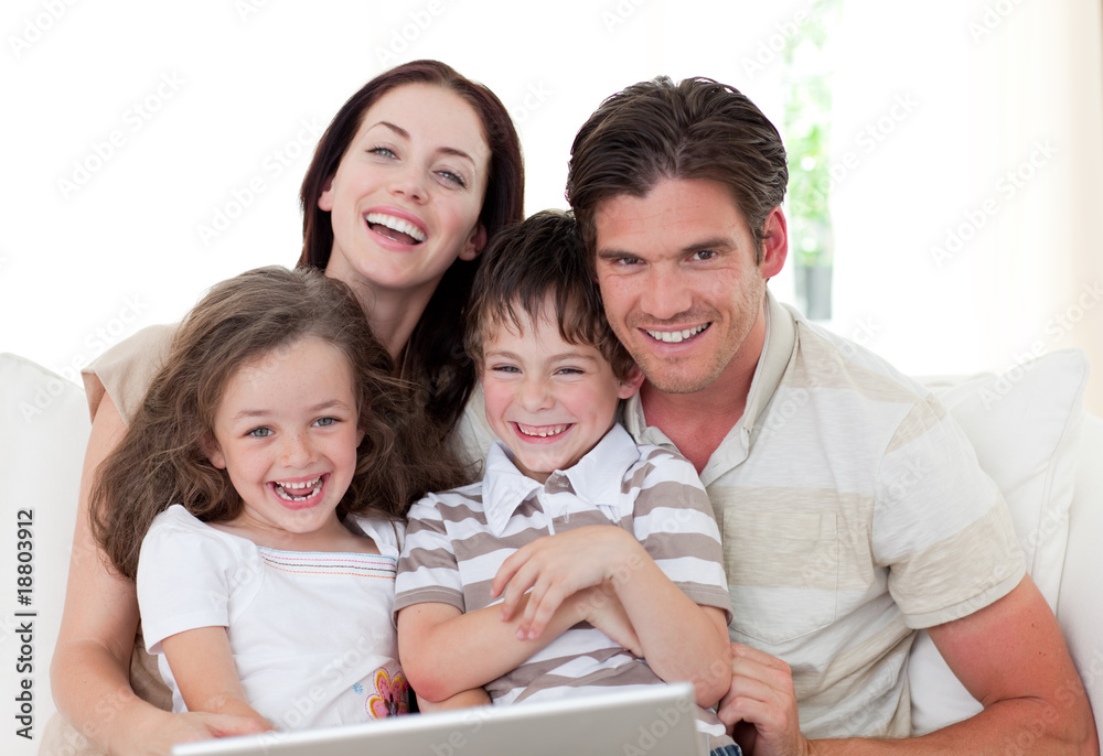 Smiling family using a laptop in the living-room