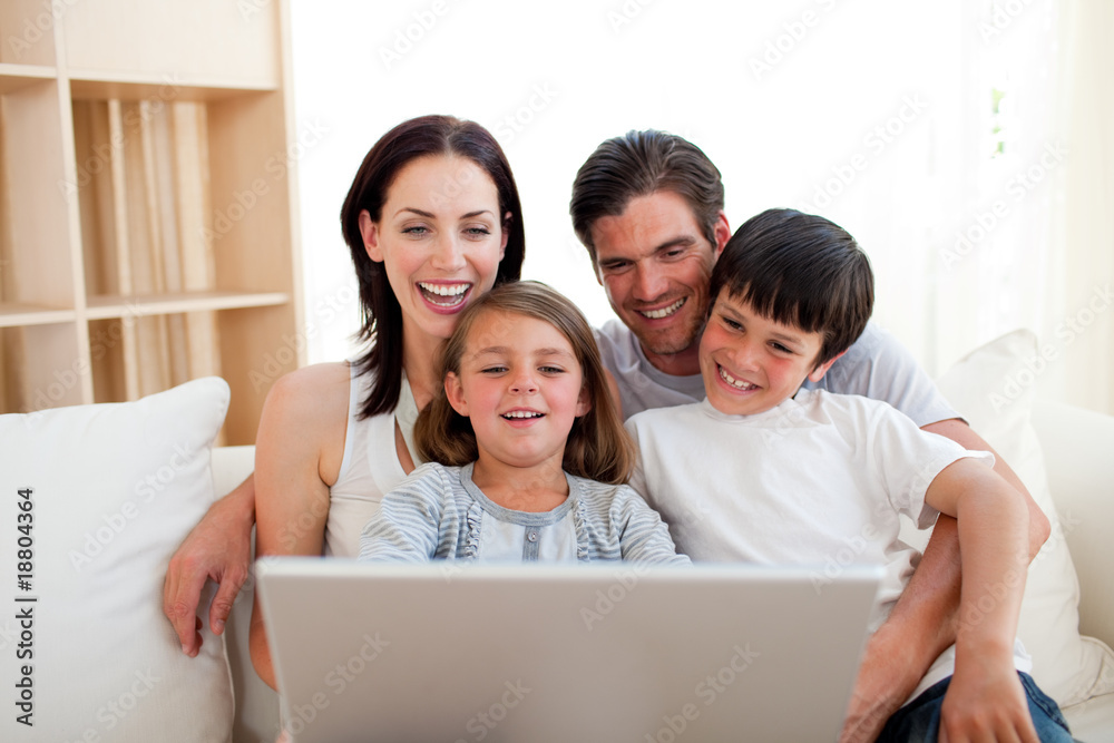 Smiling fanily using a laptop on the sofa Smiling fanily using a laptop on the sofa