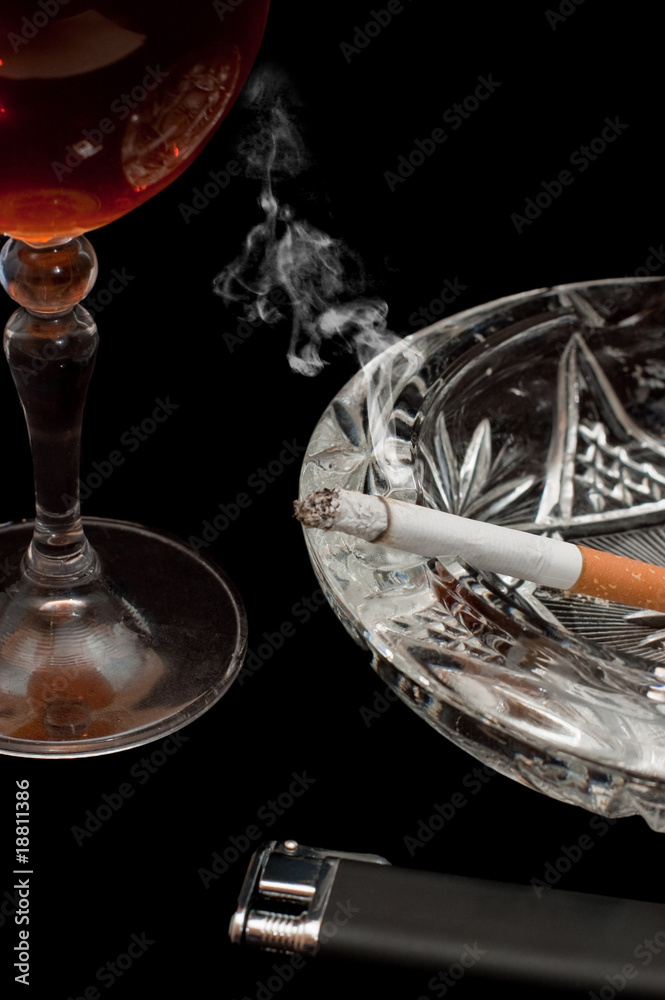 Glass of cognac and cigarette on black