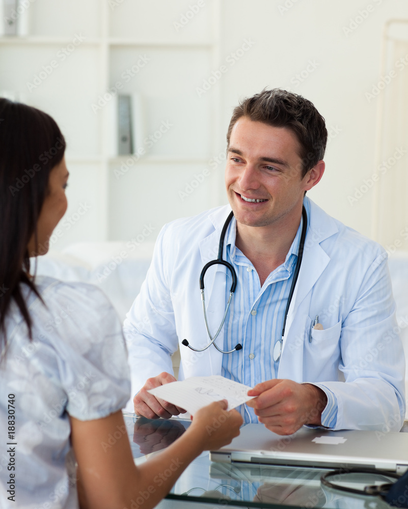 Smiling doctor giving a prescription to his female patient Smiling doctor giving a prescription to his female patient